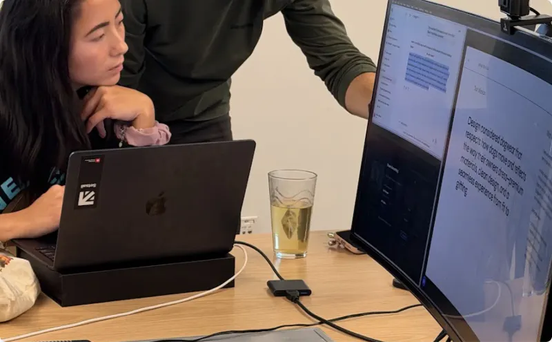 A Setsail team member at her laptop, chin on her hand, while a colleague points to a document on the monitor beside her